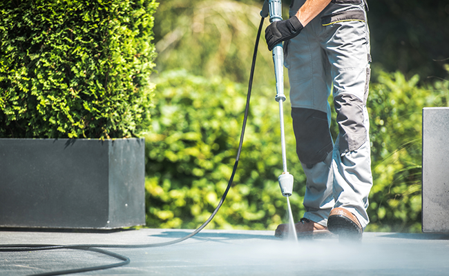 Man pressure cleaning outdoor area